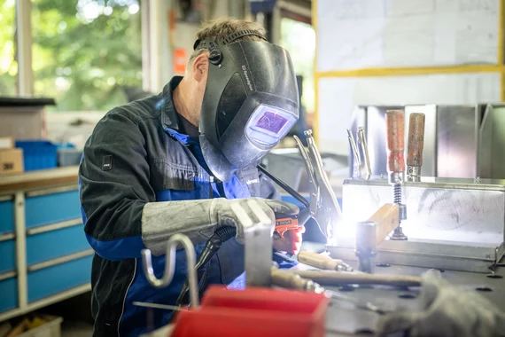 Mitarbeiter in einem metallverarbeitenden Betrieb mit Maske.