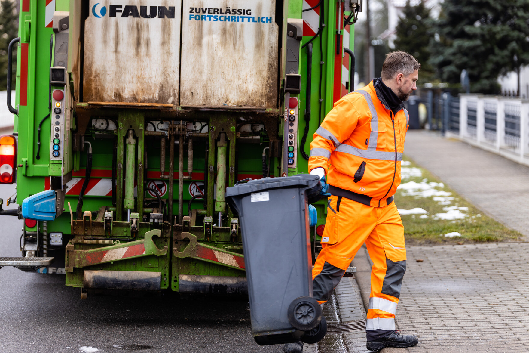 Minister Martin Dulig mit einer Mülltonne in der Hand am Müllfahrzeug