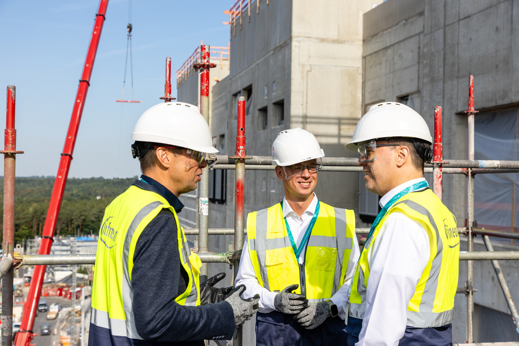 Minister Dirk Panter im Gespräch mit zwei Herren auf der Infineon-Baustelle