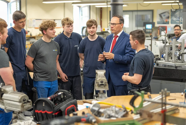 Minister Dirk Panter mit sechs Auszubildenden im Gespräch in einem Ausbildungszentrum in Leipzig.