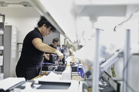 Eine Mitarbeiterin hält ein Werkzeug in der Hand und arbeitet.