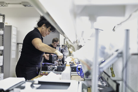 Eine Mitarbeiterin hält ein Werkzeug in der Hand und arbeitet.