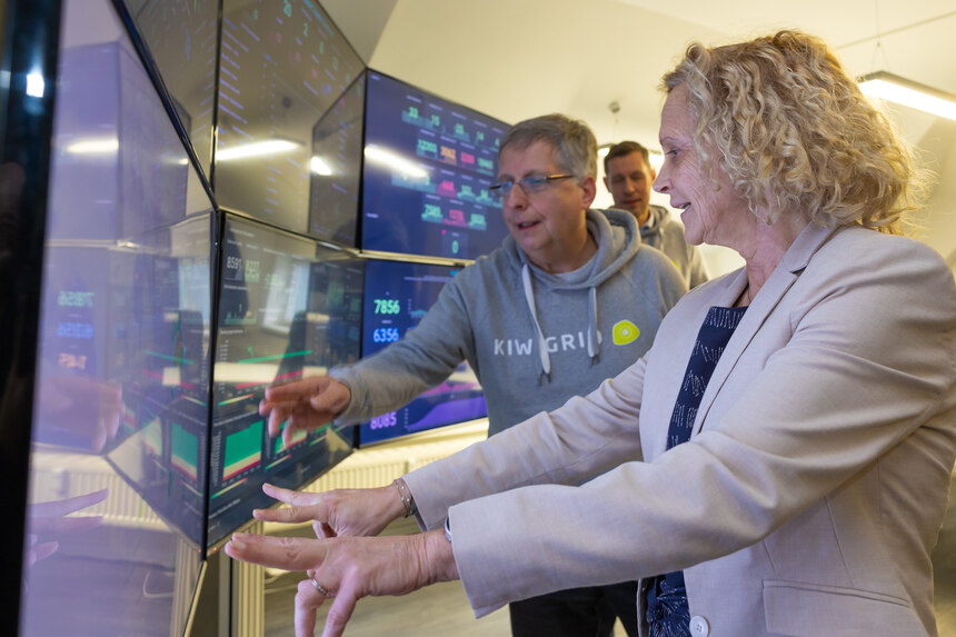 Staatssekretärin Ines Fröhlich steht neben einem Mann und zeigt auf einen Monitor.