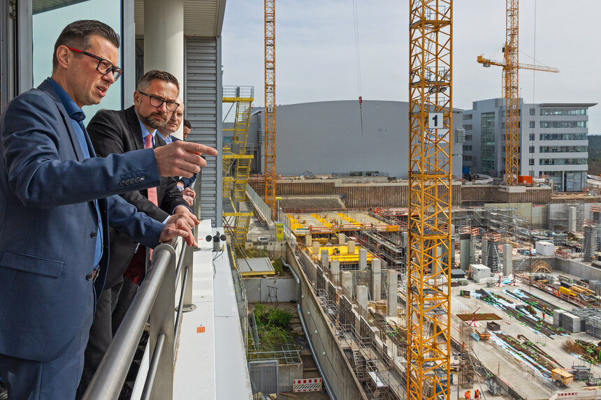 Minister Martin Dulig blickt mit einem Herren auf eine Baustelle.