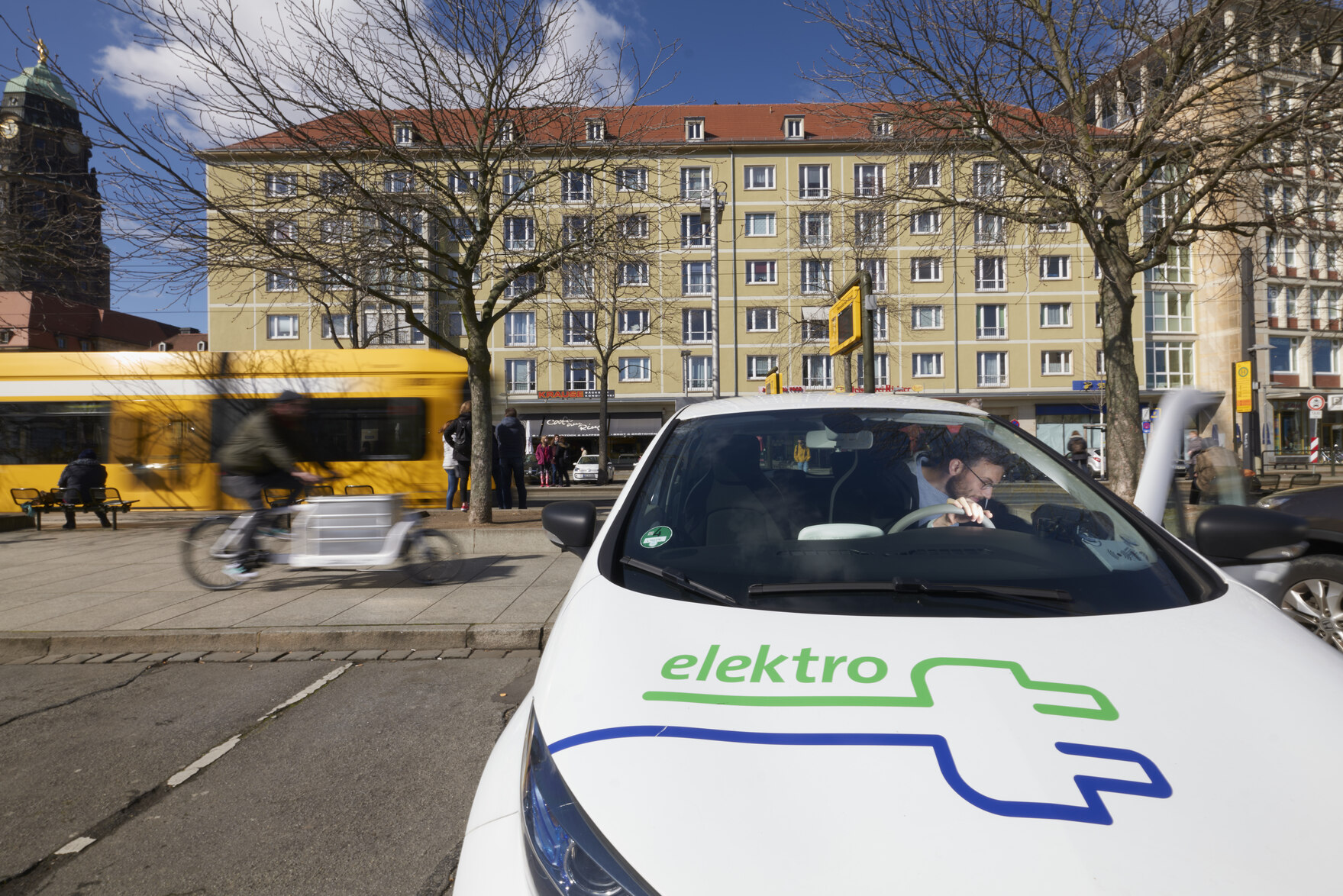 Verschiedene Formen der Mobilität: Elektroauto, Lastenfahrrad, Straßenbahn