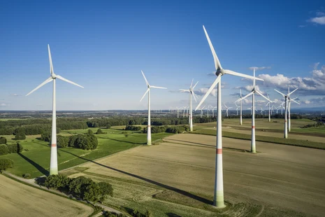 Mehrere Windräder auf Feldern.