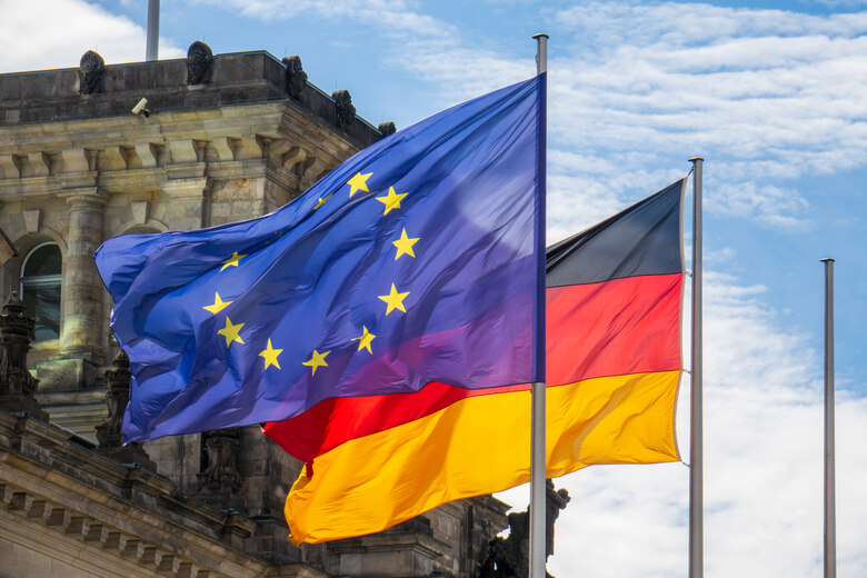 Die Flagge der Europäischen Union weht neben der Flagge der Bundesrepublik Deutschland vor einem Gebäude.