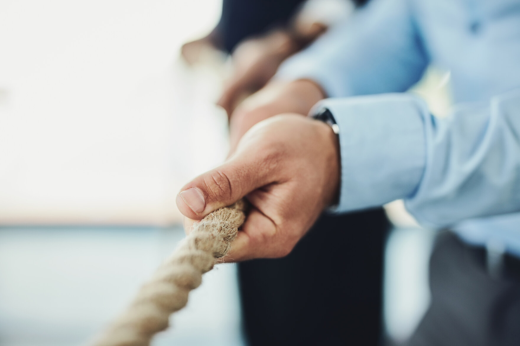 Hände von Menschen in Businesskleidung ziehen an einem Tau